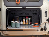 Alu-Cab storage compartment with camping gear inside a vehicle with the Alu-Cab Rear Door Drop Down Table, fitted