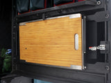 Wooden cutting board with metal handle, part of the Alu-Cab Rear Door Drop Down Table, mounted to a camping vehicle