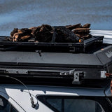 Alu-Cab Roof Rack Tray mounted on top of a Hard Shell Gen3 Rooftop Tent, in a wilderness setting