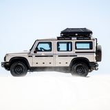 Alu-Cab RT-2S Rooftop Tent mounted on a Camp4x4 rental vehicle, in sand dunes