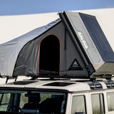 A close up view of the Alu-Cab RT-2S Rooftop Tent mounted on a Camp4x4 rental vehicle at the beach