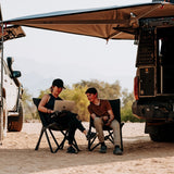 Two people sitting under a vehicle mounted an Alu-Cab 270 degree Shadow Awning. Camp4x4. camp 4x4, overlanding, camping. Double Cab. Single Cab. Extra Cab