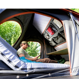 camp4x4.co.za Someone sitting in an Alu-Cab Gen3-R Hardshell Rooftop Tent with the Backrest up and the internal drop-down table in use.