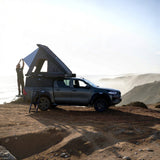 camp4x4.co.za Someone setting up an Alu-Cab Gen3-R Hardshell Rooftop Tent with mountains in the background
