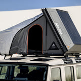 A close up view of the Alu-Cab RT-2S Rooftop Tent mounted on a Camp4x4 rental vehicle at the beach