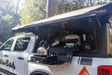Ford Ranger double cab off-road vehicle, fitted with the Alu-Cab 270 Shadow Awning, the Alu-Cab Contour Canopy DC, and the Contour Canopy Kitchen Kit, on display in the woods