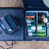 Dometic CFX5 75DZ duel zone portable fridge with the doors open with drinks and a power bank on a concrete surface