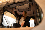 Woman inside a Front Runner Rooftop Tent adjusting the interior space