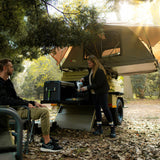 Two people with a Camping Trailer fitted with a Front Runner Rooftop Tent in a forest setting