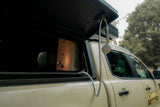 Side view of a beige Camp4x4 Rental vehicle with trees in the background.