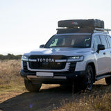 Front Runner Feather-Lite II Rooftop Tent attached to a Camp4x4 rental Toyota Land Cruiser on a white background.