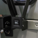 Close-up of a Front Runner Land Rover Defender 90/110 Single Gas Bottle Bracket with a square black logo labeled 'FRONT RUNNER' in white text, attached to a vehicle frame.
