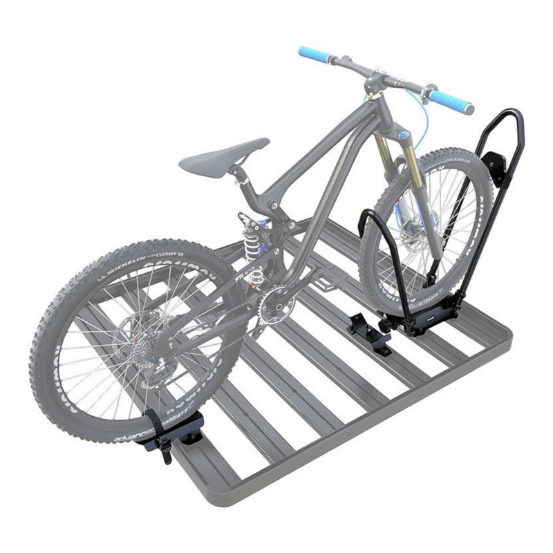 A gray slatted roof rack on a white background, shown with a semi-transparent gray mountain bike secured to a Front Runner Pro Bike Carrier.