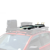 Two surfboards with black fins attached to a Front Runner Pro Surfboard, Windsurf & Paddle Board Carrier on a roof rack mounted on a red vehicle, shown against a plain white background.