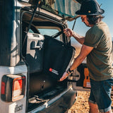 Man opening the door of a vehicle with 'Front Runner' branding in an outdoor setting.