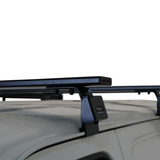 A Front Runner Suzuki Eeco (2023-Current) Triple Load Bar Kit mounted to the roof of a light gray vehicle, shown against a plain white background.