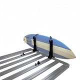 A blue and cream surfboardstrapped to a Front Runner Vertical Surfboard Carrier, mounted on a black roof rack, shown against a plain white background.