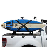 A blue and cream surfboard secured on a black roof rack mounted to the bed of a white pickup truck, with the Front Runner Vertical Surfboard Carrier.