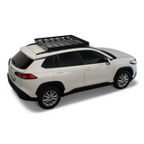 A white SUV shown from a three-quarter rear angle on a light gray studio background, fitted with a Front Runner Toyota Corolla Cross (2020-Current) Slimline II Roof Rack Kit
