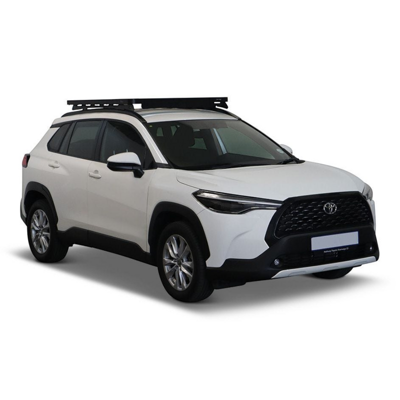 A white Toyota SUV with a black Front Runner Toyota Corolla Cross (2020-Current) Slimline II Roof Rack Kit, shown from a three-quarter front angle on a clean white background.