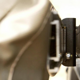 Close-up detail shot of a black textured Front Runner Series Easy-Out Awning Bracket attached to a metallic silver surface, with shallow depth of field.