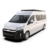 A white Toyota Hiace van with a black Front Runner Series Toyota HiAce SLWB High Roof (2019-Current) Slimpro Roof Rack Kit, shown from a three-quarter front angle on a solid white background.