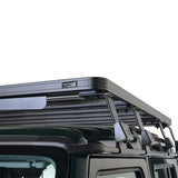A black Front Runner Ineos Grenadier Quartermaster Slimline II Roof Rack Kit mounted on the roof of a dark vehicle, shown against a solid white background.