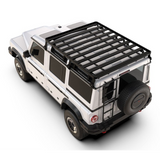 A black Front Runner Ineos Grenadier (2022-Current) Slimline II 3/4 Roof Rack Kit mounted on the roof of a white SUV, shown from a high-angle three-quarter view on a white background.