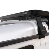 A Front Runner Ineos Grenadier (2022-Current) Slimline II 3/4 Roof Rack Kit mounted to the side of a white vehicle, shown in a clean studio-style close-up. Small labels on the hardware read 'FORT SMART'.
