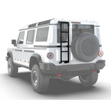 A white off-road vehicle shown from the rear three-quarter angle on a light gray studio background, with a Front Runner Ineos Grenadier (2022-Current) Ladder leading up to the back door and a spare tire mounted on the rear.