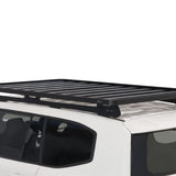 A black Front Runner Toyota Land Cruiser 300 Slimline II Roof Rack Kit mounted on the roof of a white vehicle, shown against a plain white background.