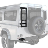 A Front Runner Land Rover Defender 90/110 (1983-2016) Ladder mounted on the rear side of a white off-road vehicle, with a spare tire visible on the back.