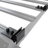 Close-up of a silver metal roof rack frame with black Front Runner Series Slimsport Side Mount Accessory Bracket and bolts, shown on a clean white background.