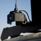 A black Front Runner Series Slimsport Side Mount Accessory Bracket / Small, mounted on a dark vehicle frame against a blue sky.