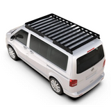 A black Front Runner Volkswagen T5 Transporter SWB (2003-2015) Slimline II Roof Rack Kit mounted on the roof of a white Volkswagen van, shown from a high-angle studio perspective on a white background.