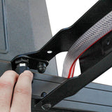 Close-up of a Front Runner Tap Extension Brackett with a thumbscrew onto a dark gray frame, with a white mesh hose and red stripe visible.
