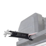 A close-up of a black roof-mounted Front Runner Tap Extension Bracket attached to a faded out vehicle roof rack, with a small visible Front Runner logo on the bracket.