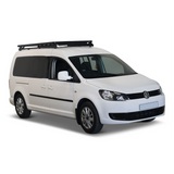 A white Volkswagen Caddy van with a black Front Runner Volkswagen Caddy LWB (2015-2020) Slimline II Roof Rack Kit, shown from a three-quarter front angle on a clean white background.