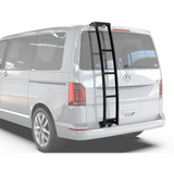 A black Front Runner Volkswagen T5/T6 Transporter Ladder mounted on the rear window of a silver Volkswagen van, shown on a clean white background.