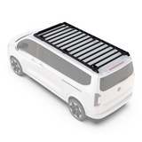 White van with a black Front Runner Volkswagen T7 Transporter Caravelle LWB (2025-Current) Slimsport Roof Rack Kit / Light Bar Ready, on a white background