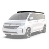 A white Volkswagen camper van with a black Front Runner Volkswagen T7 Transporter Caravelle LWB (2025-Current) Slimsport Roof Rack Kit, shown from a three-quarter front angle on a clean white background.