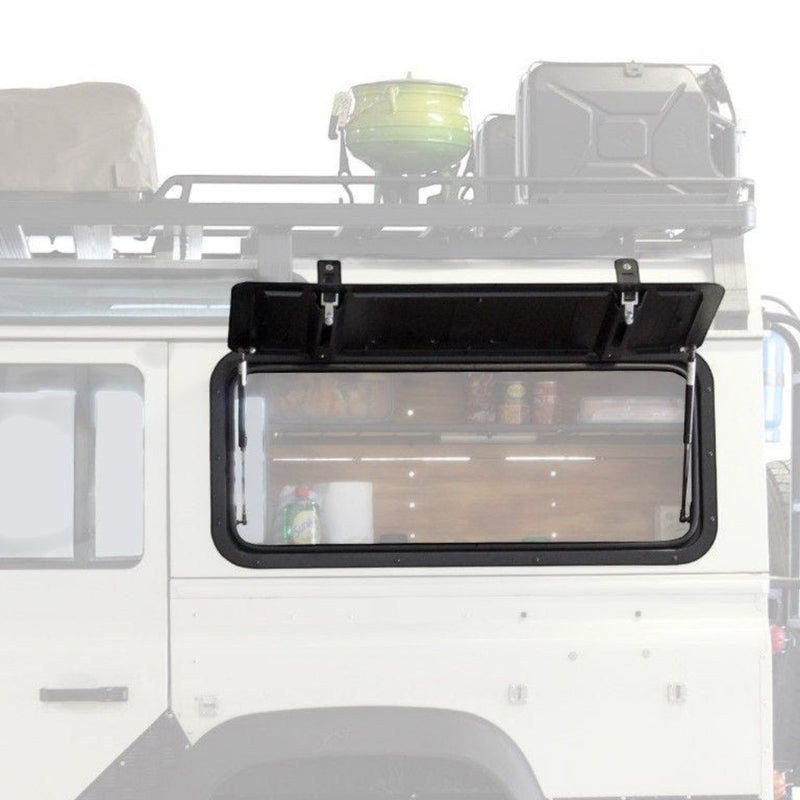 A black Front Runner Land Rover Defender (1983-2016) Gullwing Window / Aluminium, mounted on the side of a white vehicle, with its door open to reveal a storage compartment inside.