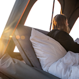 Person lying in an Alu-Cab Gen3.R rooftop tent with a fitted Backrest accessory. camp 4x4