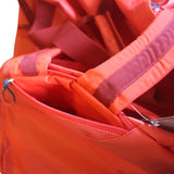 Close-up of a bright orange-red 120lt MEERKAT Travel bag showing a zippered pocket, webbing strap, and interior lining.