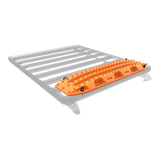 An orange MaxTrax MKII with black knobs, shown mounted on a silver metal roof rack against a white background.