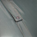 Close-up detail of a teal-green MEERKAT Nylon Folding Mattress showing a diagonal flap with a dark metal snap button and contrast stitching.