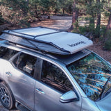 RoofPod Rooftop tent on a silver SUV with ladder in a forest setting