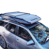 RoofPod Rooftop tent on a silver SUV with ladder in a forest setting