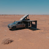 Car with a RoofPod Awning side, mounted tent attached to it in the desert 