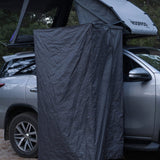 Car with a rooftop tent and a RoofPod Shower/Privacy Cube attached in a forest setting